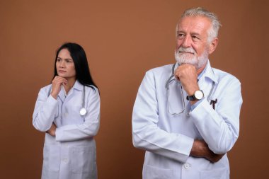 Olgun çok etnik gruptan oluşan çift doktorlar kahverengi zemin karşı