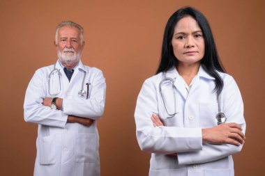 Olgun çok etnik gruptan oluşan çift doktorlar kahverengi zemin karşı
