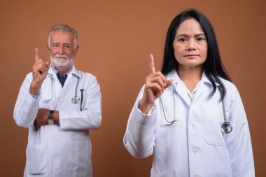 Olgun çok etnik gruptan oluşan çift doktorlar kahverengi zemin karşı
