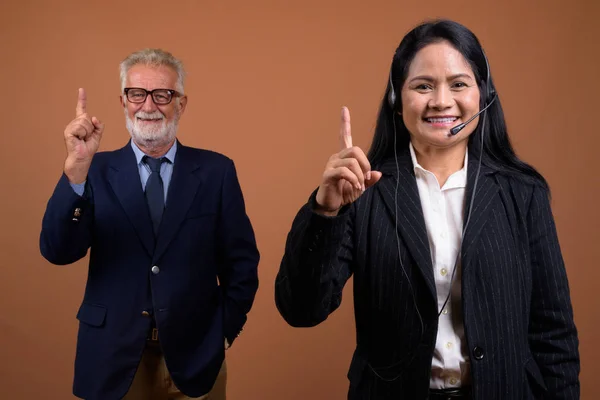 Mogen multietniska business par mot brun bakgrund — Stockfoto