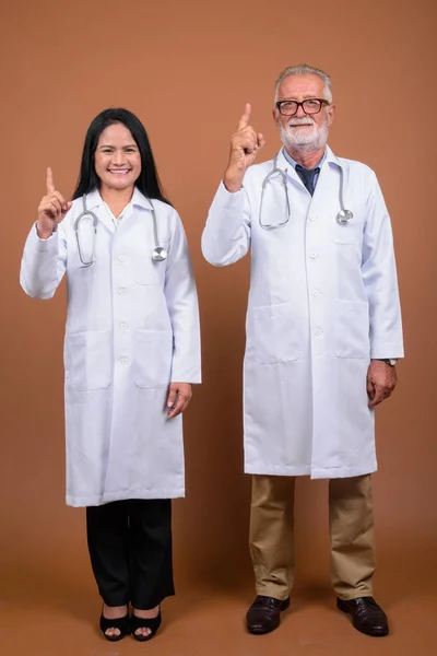 Maduro multi-étnico pareja médicos contra el fondo marrón —  Fotos de Stock