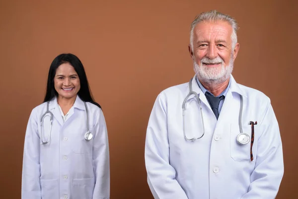 Maduro multi-étnico pareja médicos contra el fondo marrón —  Fotos de Stock