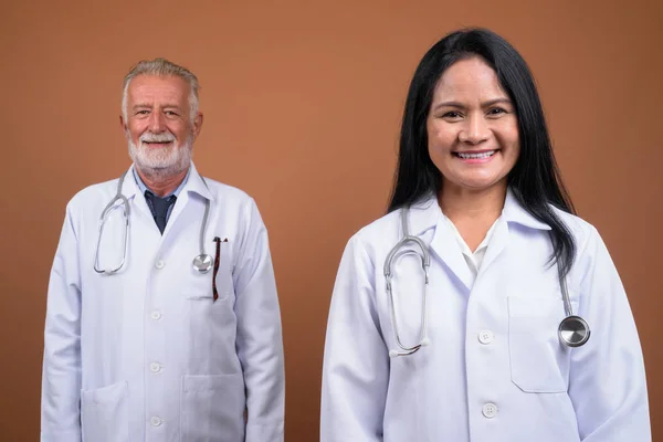 Maduro multi-étnico pareja médicos contra el fondo marrón —  Fotos de Stock