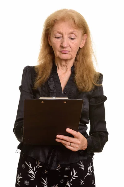 Studio shot of senior businesswoman reading on clipboard — Stock Photo, Image