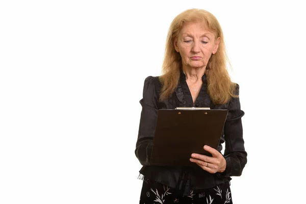 Studio shot of senior businesswoman reading on clipboard — Stock Photo, Image