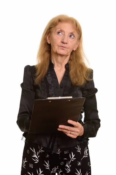 Studio shot of senior businesswoman holding clipboard while thin — Stock Photo, Image