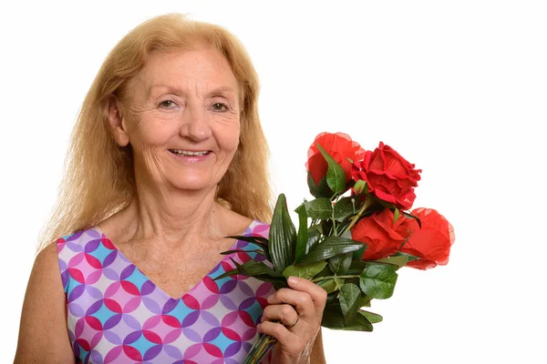 Studio skott av glad senior kvinna ler och håller röda rosor — Stockfoto