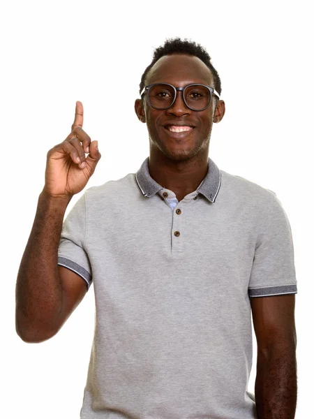 Młody szczęśliwy czarny Afrykanin człowiek uśmiecha się a wskazując palec w górę — Zdjęcie stockowe