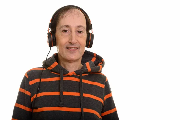 Studio shot of happy mature man smiling and listening to music — Stock Photo, Image