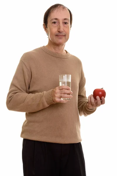 Estúdio tiro de homem maduro segurando vidro de água e maçã vermelha — Fotografia de Stock