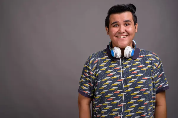 Joven hombre multiétnico con auriculares contra el fondo gris — Foto de Stock