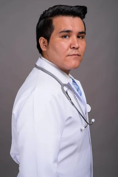 Молодий багатоетнічний лікар на сірому фоні — стокове фото