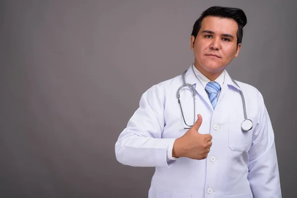 Joven médico hombre multiétnico contra el fondo gris —  Fotos de Stock