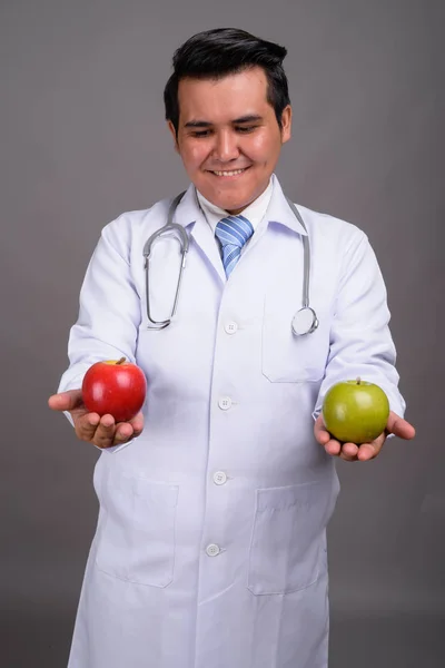 Joven médico hombre multiétnico contra el fondo gris — Foto de Stock