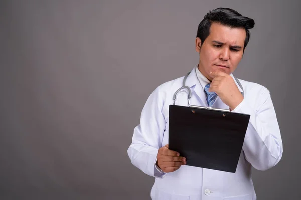 Joven médico hombre multiétnico contra el fondo gris — Foto de Stock