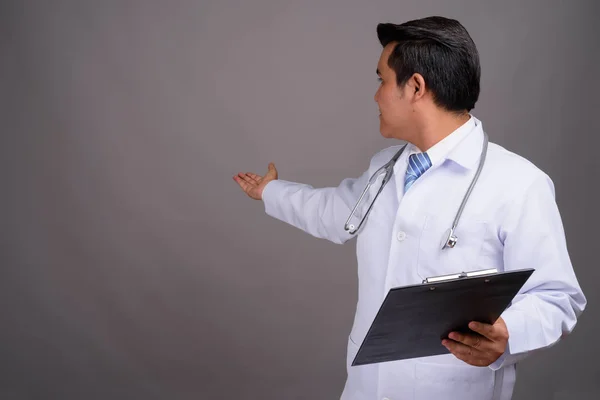 Young multi-ethnic man doctor against gray background — Stock Photo, Image