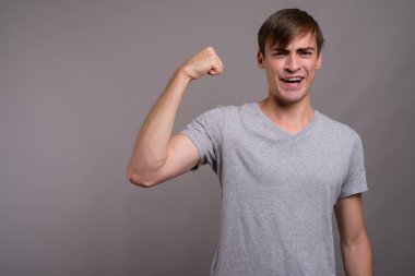 Genç yakışıklı adam gri arka planda jimnastiğe hazır.