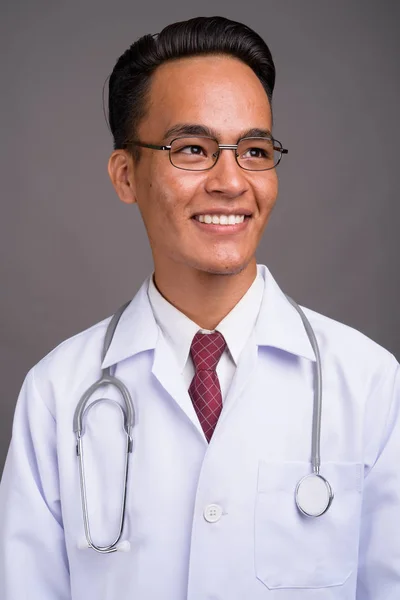 Joven guapo indio hombre médico contra gris fondo — Foto de Stock