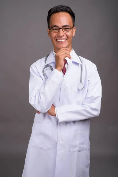 Joven guapo indio hombre médico contra gris fondo — Foto de Stock