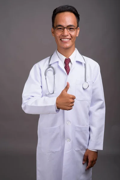 Joven guapo indio hombre médico contra gris fondo — Foto de Stock