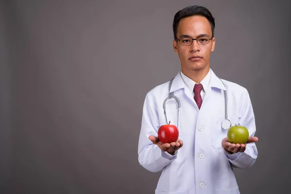 Joven guapo indio hombre médico contra gris fondo —  Fotos de Stock