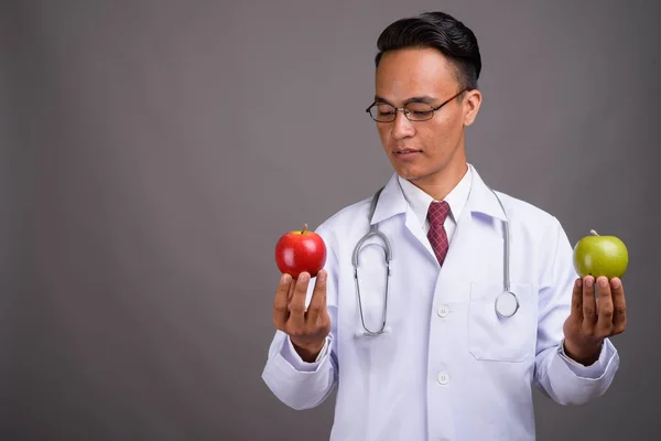 Genç yakışıklı Hintli Doktor gri bir arka plana dayanır — Stok fotoğraf