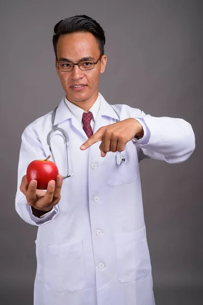 Junger hübscher indischer Arzt vor grauem Hintergrund — Stockfoto