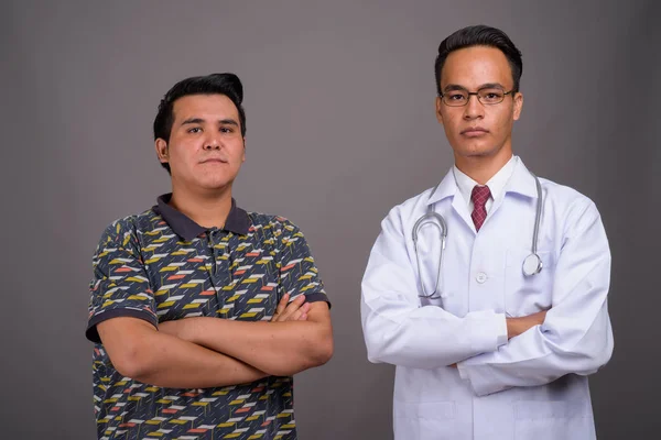 Jovem multi-étnico homem e jovem indiano médico contra cinza — Fotografia de Stock