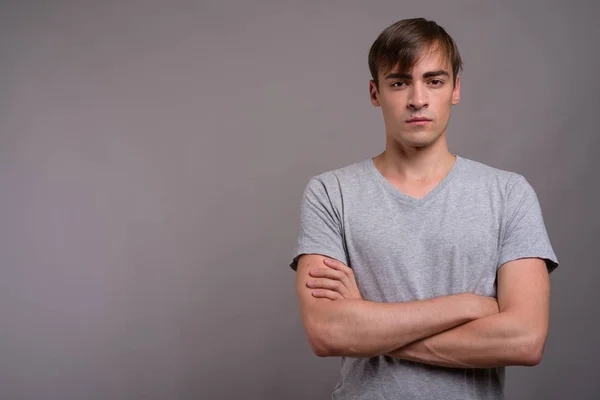 Young handsome man ready for gym against gray background — Stock Photo, Image