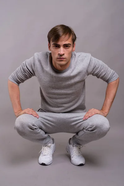 Jeune homme beau prêt pour la salle de gym sur fond gris — Photo