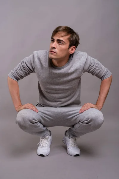 Young handsome man ready for gym against gray background — Stock Photo, Image