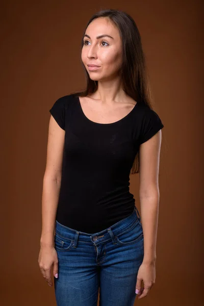 Studio shot of young beautiful woman against brown background — Stock Photo, Image