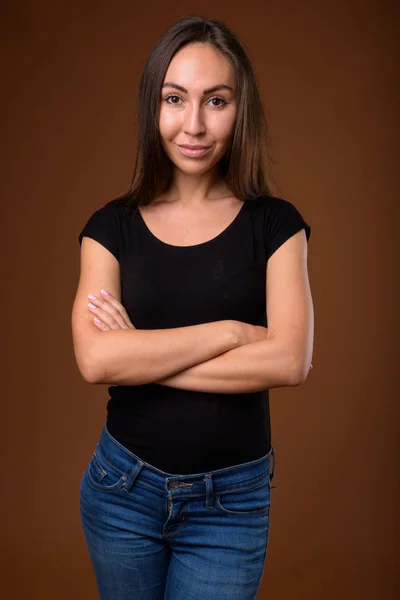 Studio shot of young beautiful woman against brown background — Stock Photo, Image