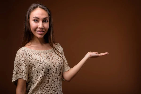 Studio záběr Mladá krásná žena proti hnědým pozadím — Stock fotografie