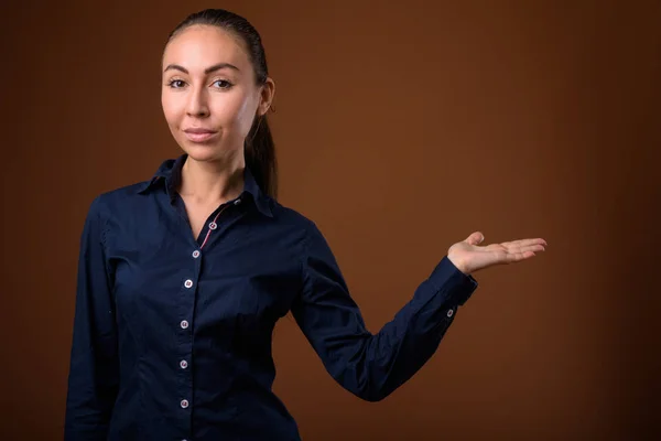 Studio shot of young beautiful businesswoman against brown backg — Stock Photo, Image