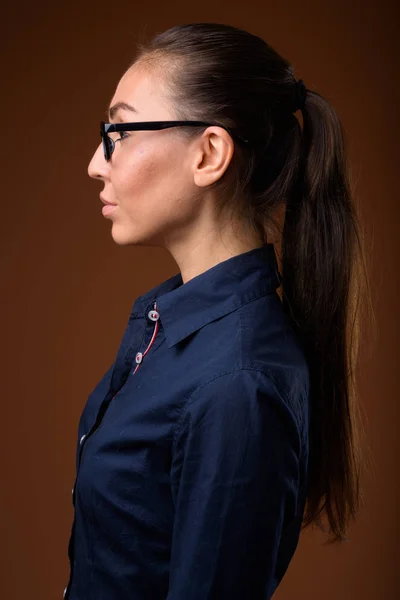 Young beautiful businesswoman wearing eyeglasses against brown b — Stock Photo, Image