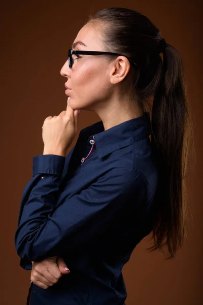 Junge schöne Geschäftsfrau mit Brille gegen braune B — Stockfoto