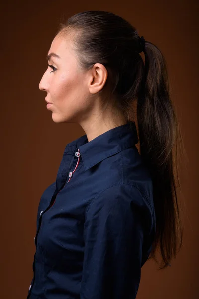 Studio shot van jonge mooie zakenvrouw tegen bruin backg — Stockfoto