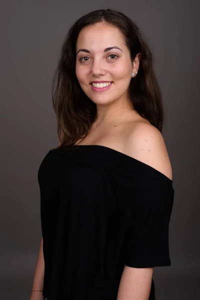 Young beautiful woman wearing black off-shoulder top against gra — Stock Photo, Image