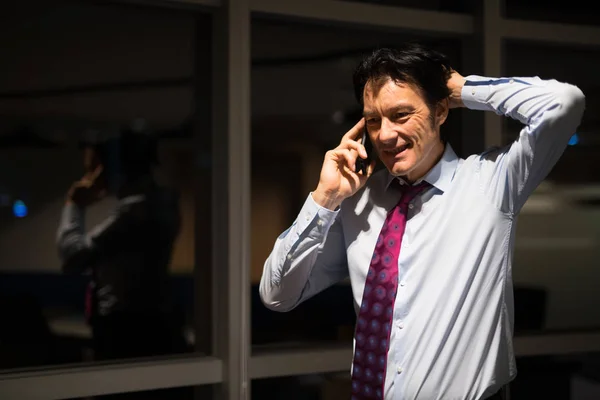 Érett üzletember irodájában éjszakai beszélő-ra mozgatható telefon — Stock Fotó
