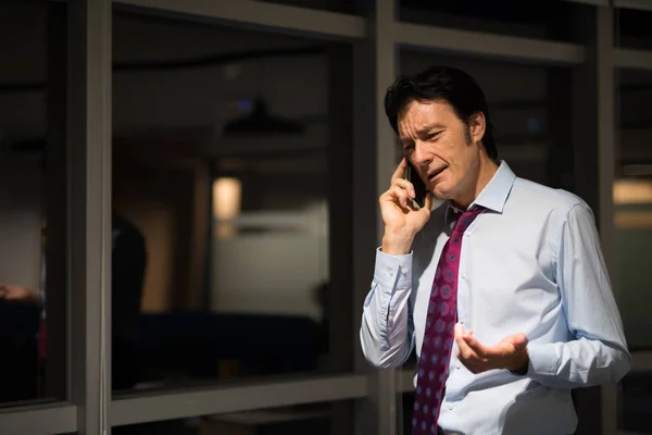 Mature Businessman In Office At Night Talking On Mobile Phone — Stock Photo, Image