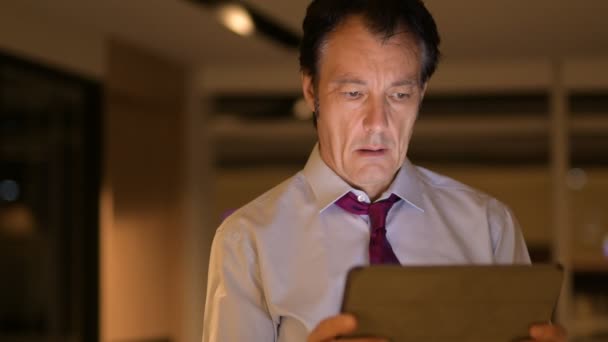 Reifer Geschäftsmann nachts mit digitalem Tablet-Computer im Büro — Stockvideo