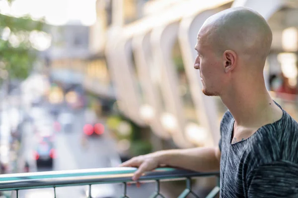 Profile view of young handsome bald man thinking in city — Stock Photo, Image