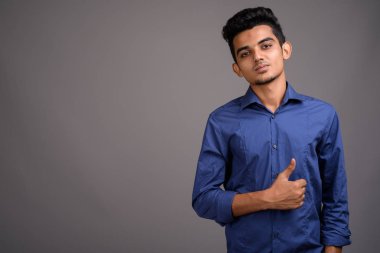 Genç Hintli işadamı gri bir arka plana dayanır