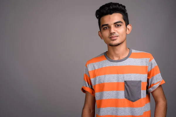 Young Indian man against gray background