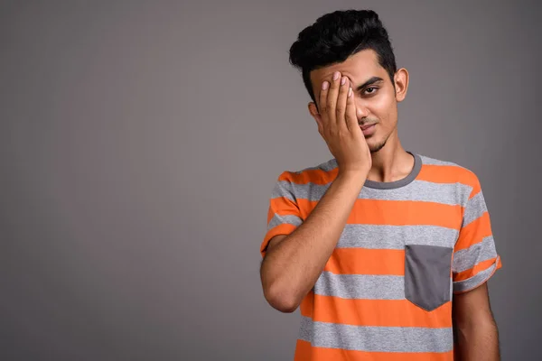 Jonge Indiase man tegen een grijze achtergrond — Stockfoto