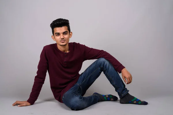 Young Indian man against gray background