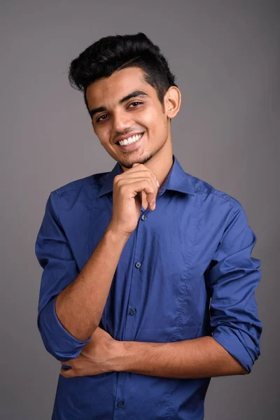 Jonge Indiase zakenman tegen de grijze achtergrond — Stockfoto