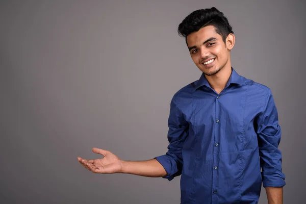 Молодий індійський бізнесмен проти сірий фон — стокове фото