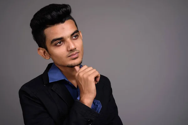 Young Indian businessman against gray background